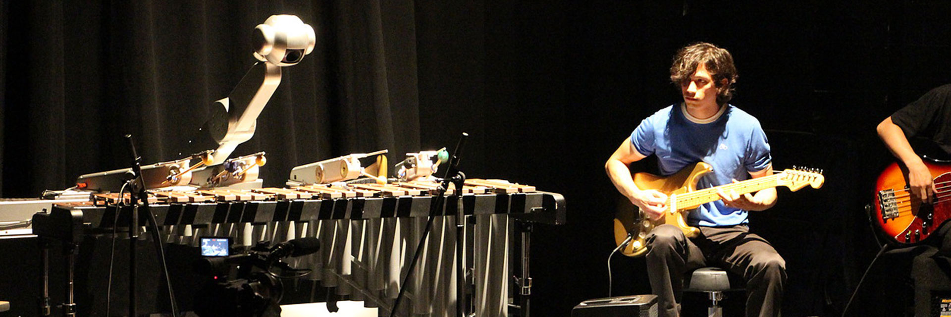 A music technology graduate student plays guitar with a marimba-playing robot.