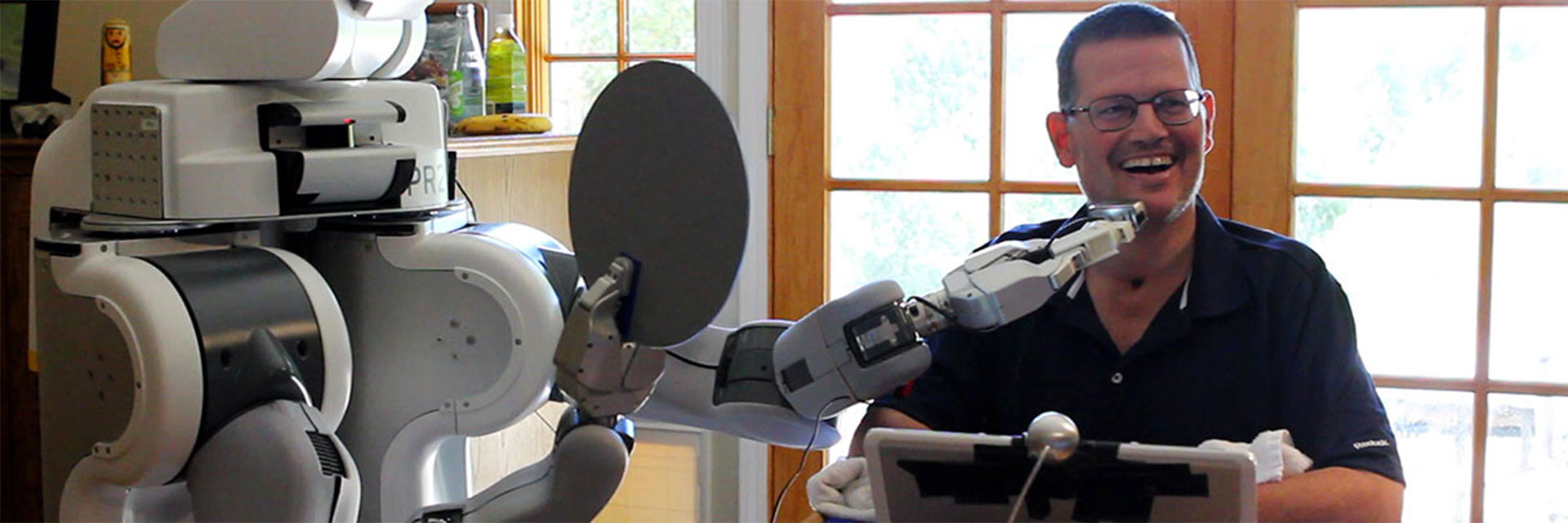 A quadriplegic man gets help shaving his face from a robot. 