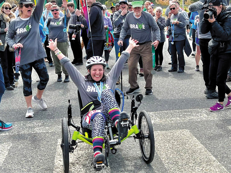 Andrea Lytle Peet crossing finish line in a recumbent bike with crowd behind her